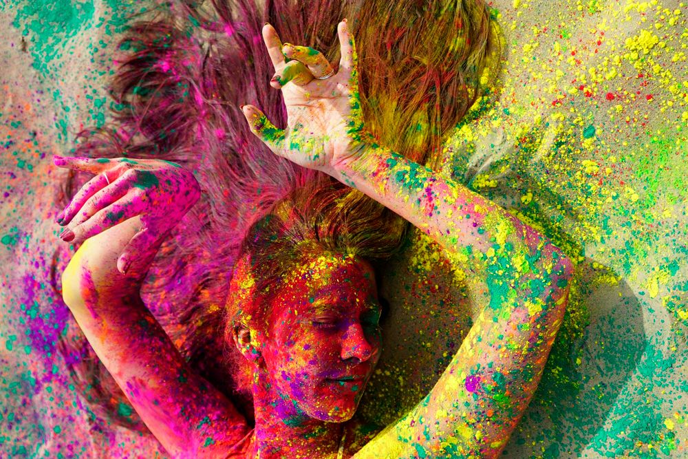 Foto van een vrouw gehuld in allerlei kleuren verfspetters.