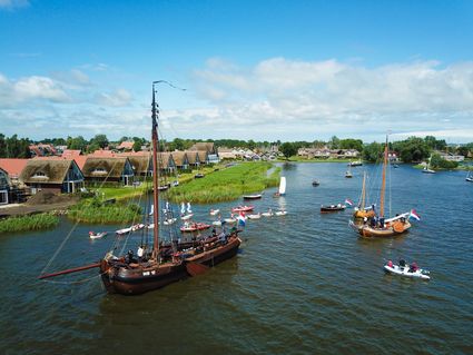 Het skûtsje van Heeg met als achtergrond huizen en zeilboten.