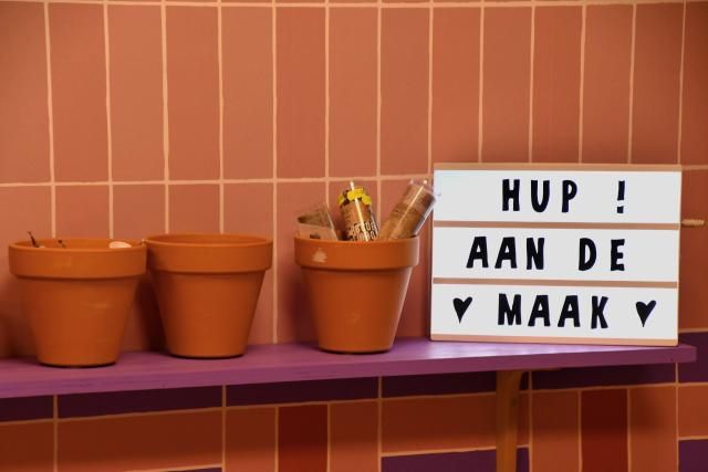 Vrije tijd winkel MAAK Woerden in Woerden, regio Groene Hart, detail van terracotta bloempotten en lichtbak met tekst “Hup aan de maak” als creatieve inspiratie voor hobby, knutselen en DIY projecten.