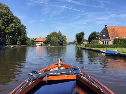 houten boot vaart met blauwe lucht door broek.