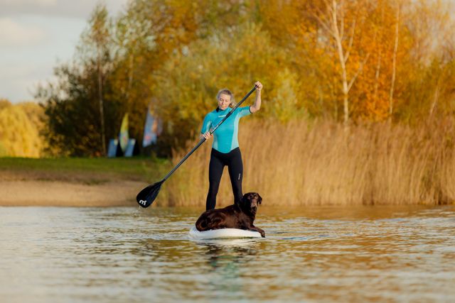vrouw suppend met hond liggend op de plank.