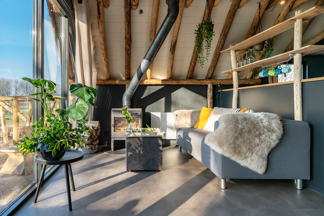 Das gemütliche Wohnzimmer des Baumhauses d'Olde Kamp. Vom Sofa aus haben Sie durch die großen Fenster einen fantastischen Blick auf die Natur in der Umgebung.