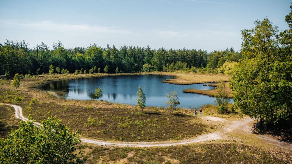 Twee vrouwenkijken uit over een ven in een natuurgebied.