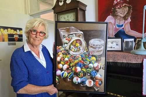 Een foto van een vrouw met een schilderij in haar handen