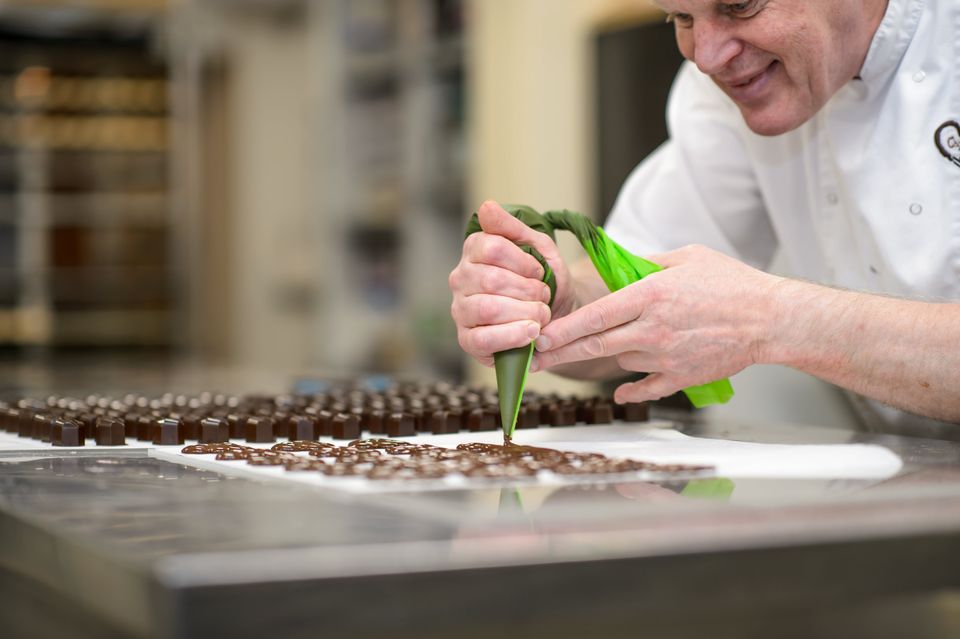 Chocolatier decoreert ambachtelijke bonbons met chocolade bij Zuccotto IJsselstein.