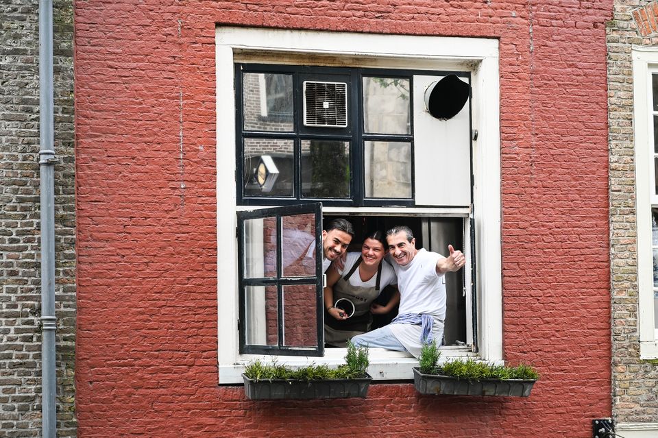 medewerkers Italiaans restaurant die uit raam hangen