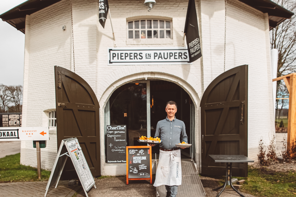 Iemand serveert eten op het terras van Piepers en Paupers in Veenhuizen.