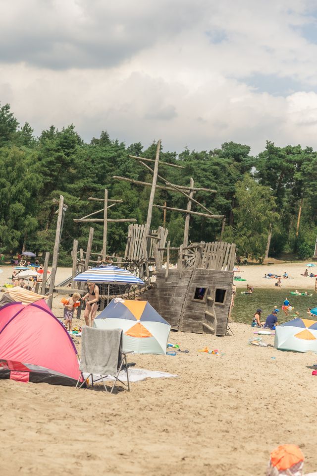 Een speeltoestel op het strand bij een bos. Bij het Henschotermeer op De Utrechtse Heuvelrug in Woudenberg.