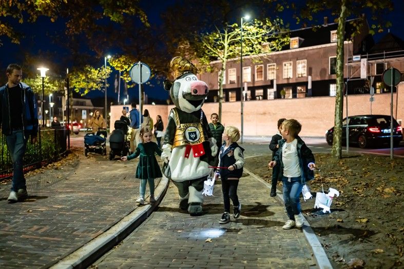 Kinderen verkleed als koeien lopen met zelfgemaakte lampionnen tijdens een gezellige lampionnenoptocht in Woerden