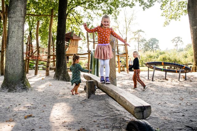 Ein Mädchen balanciert auf einem Balancierbalken auf dem Spielplatz eines Campingplatzes.