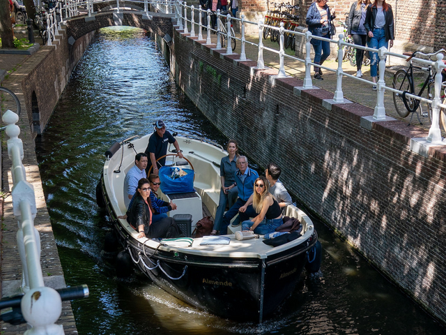 Mensen zitten in een canal hopper varend over de grachten in Delft
