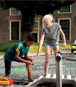 Kinderen spelen bij een watertoestel in de speeltuin