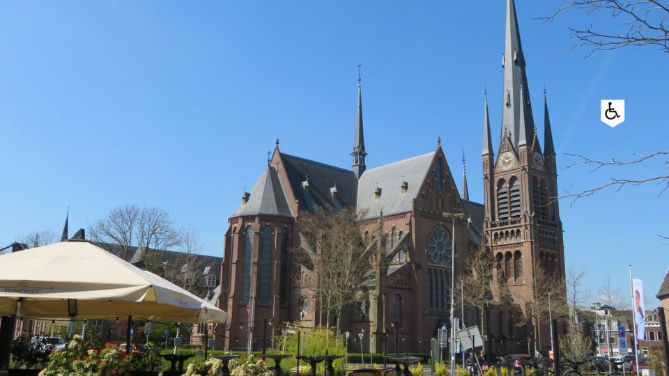Stadswandeling Woerden, provincie Utrecht, Groene Hart, zicht op de neogotische Petruskerk met hoge torenspitsen en roosvenster tijdens een historische route door de binnenstad.