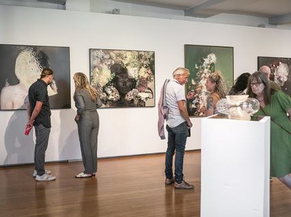 Binnen bij Kadmium Kunstcentrum Delft waar mensen kunstwerken bewonderen