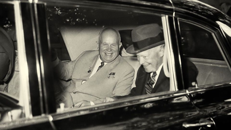 Een zwart-wit foto van twee mannen die in een auto zitten