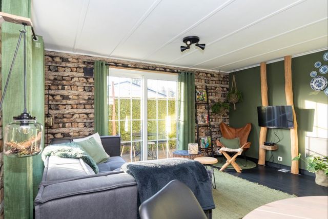 Groen met grijs, knus ingerichte woonkamer met openslaande deuren naar een tuin.