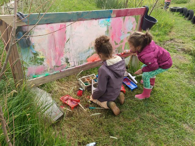 2 kinderen aan het verven op een glasplaat in de buitenlucht bij Groeiromte in Woudsend.