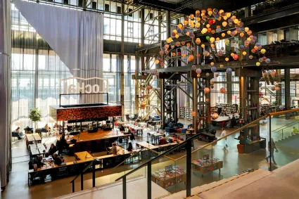 Indrukwekkend sfeerbeeld van het hoge gebouw van de LocHal met grote glazen raampartij en een mooi kunstwerk met bollen