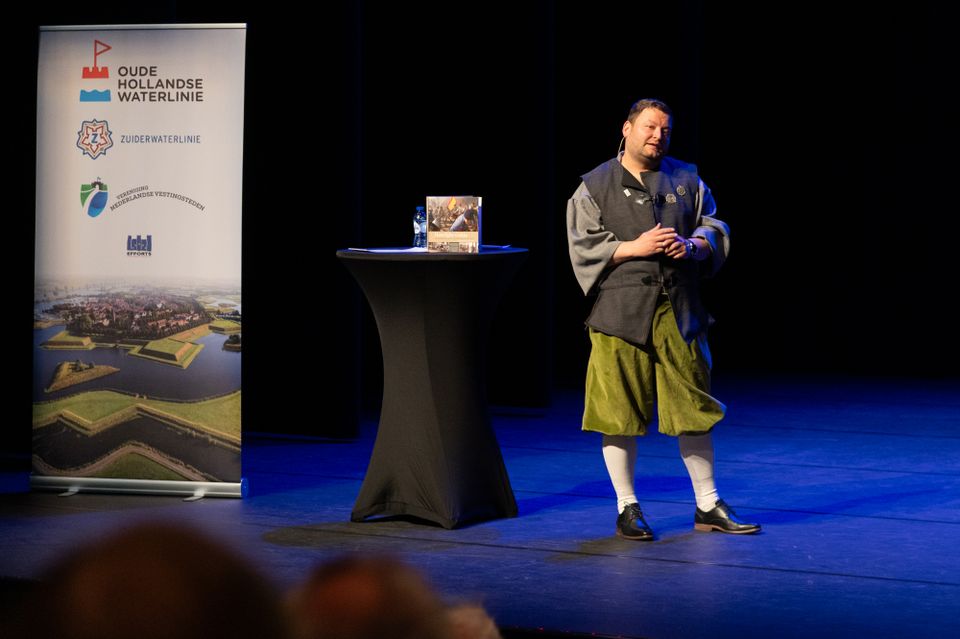 Man in kledij van vroeger vertelt iets aan publiek