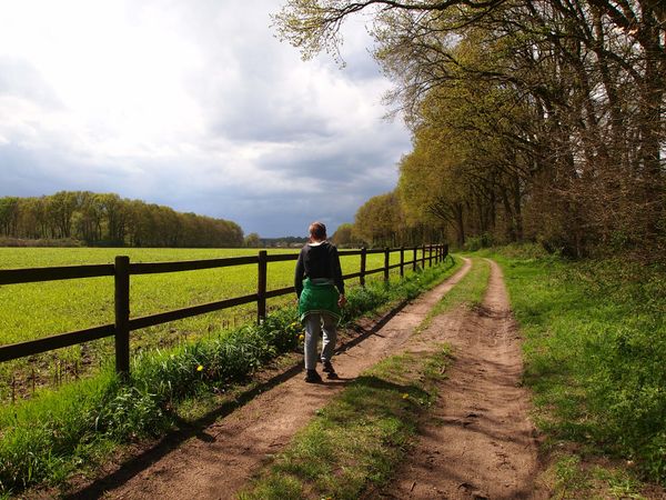 wandelaars op zandpad langs velden