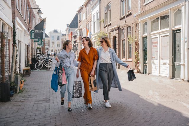 Winkelstraat in Gouda, Zuid-Holland, Groene Hart. Bezoekers shoppen met gevulde tassen langs boetieks en speciaalzaken in de historische binnenstad, populair voor een dagje winkelen en stedentrip in de kaasstad.