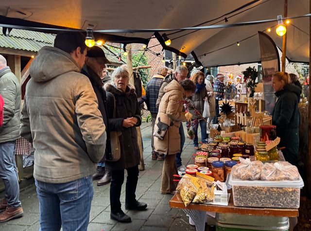 Verschillende mensen bij een kraampje vol met lekkernijen op de Greidhoeke Winterfair.