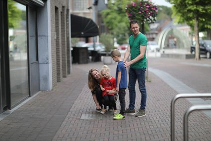 een gezin kijkt naar een bronzen plaquette op straat