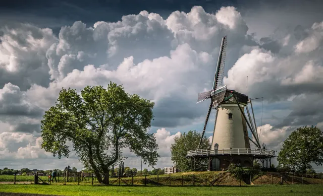 Korenmolen De Windhond in Soest staat in een groen landschap onder een bewolkte lucht.