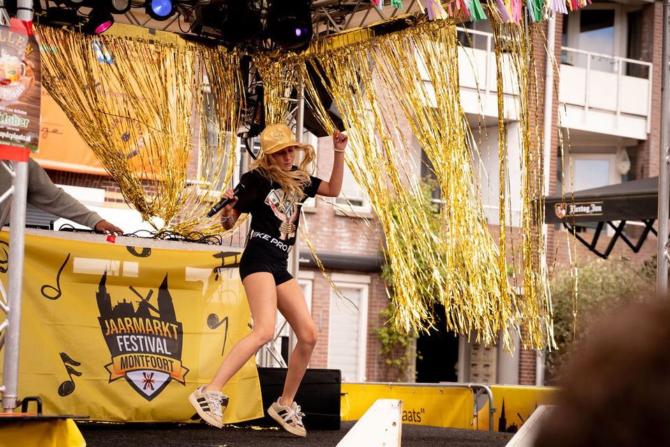 Evenement Jaarmarkt Festival Montfoort, Groene Hart, optreden op podium met dansende artiest en dj tijdens levendig dorpsfestival met muziek en entertainment.