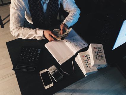 person holding money and looking at a notebook