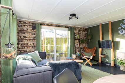 Groen met grijs, knus ingerichte woonkamer met openslaande deuren naar een tuin.