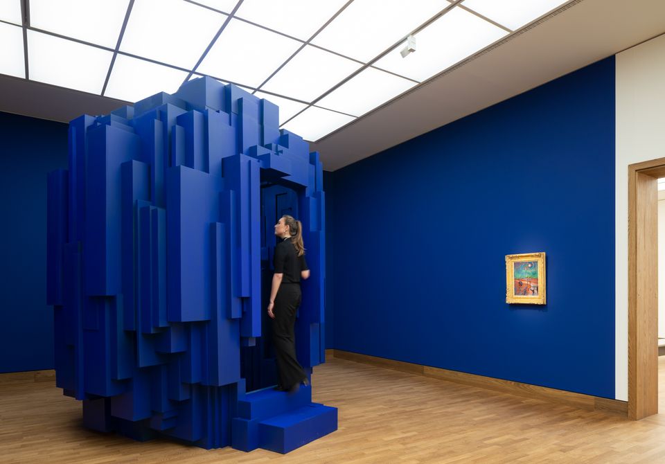 Bezoeker treed knalblauwe installatie binnen in tentoonstelling Levi van Veluw in Singer Laren.