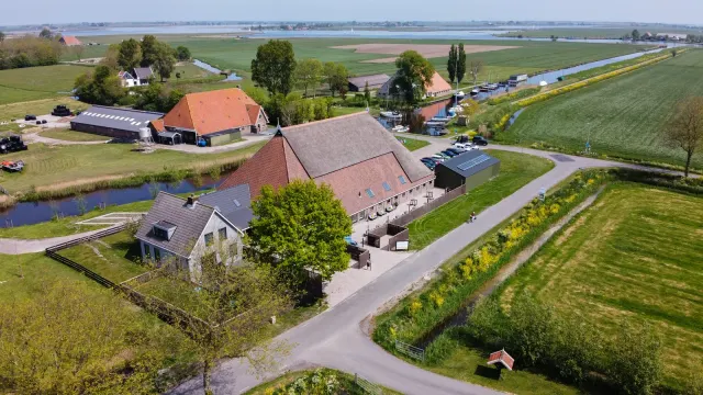 Groepaccommodatie Fries en Fruitig in Idskenhuizen van bovenaf met in de verte de Friese Meren.