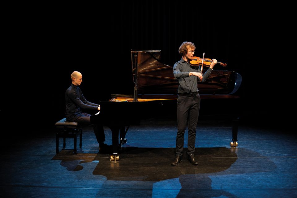 Een man achter de piano en een man met een viool