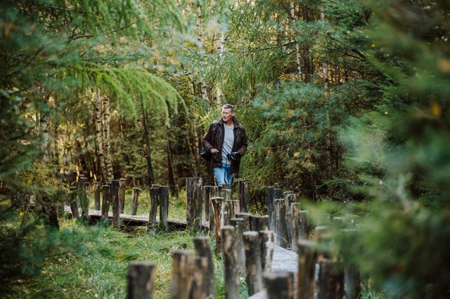 Een man loopt met een camera in zijn hand over het plankenpad in het Dwingelderveld