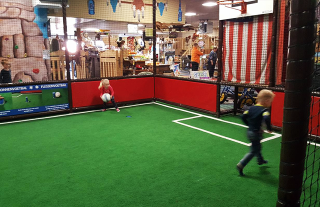 Zwei Kinder spielen Fußball in einer Panna-Käfig