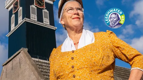 Een vrouw in klederdracht bij een kerk