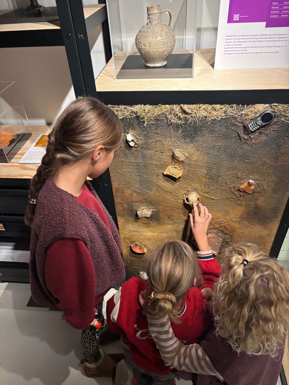 Interactieve archeologietentoonstelling in Bibliotheek Woerden, Groene Hart. Kinderen onderzoeken bodemvondsten en Romeinse scherven bij een educatieve expositie over de Limes, UNESCO Werelderfgoed en de Romeinse geschiedenis van Woerden.