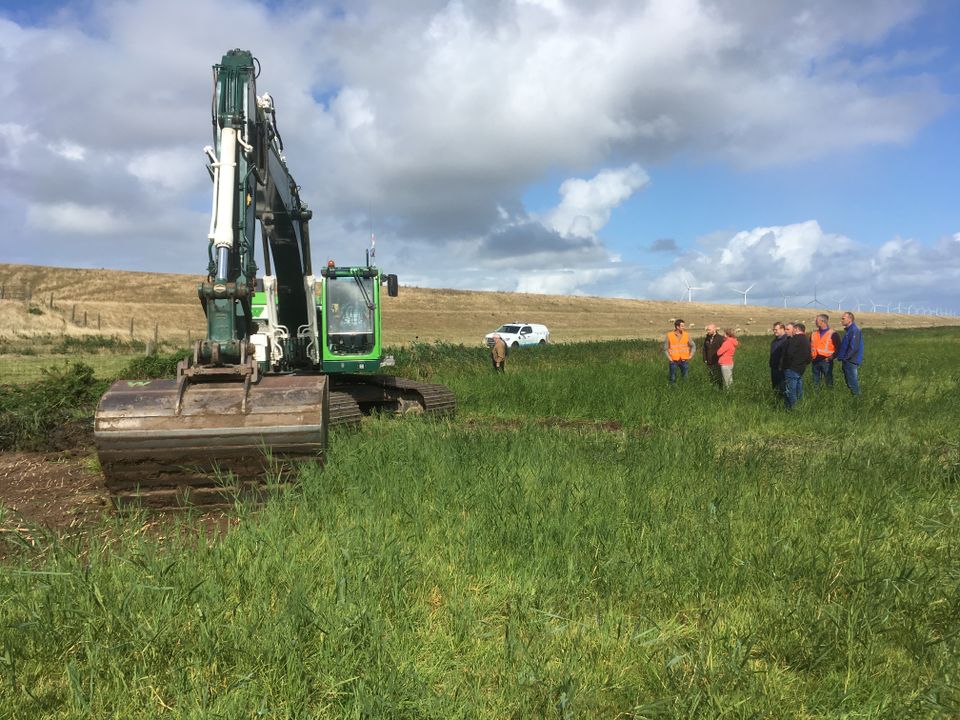 Werkzaamheden aan het Urkerveld met een graafmachine en toekijkende mensen in Urk, Flevoland