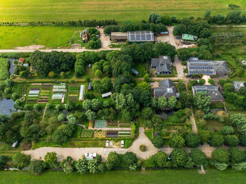 Luchtfoto van De Eemlandhoeve met moestuinen, kassen, gebouwen en groen landschap in het Groene Hart.