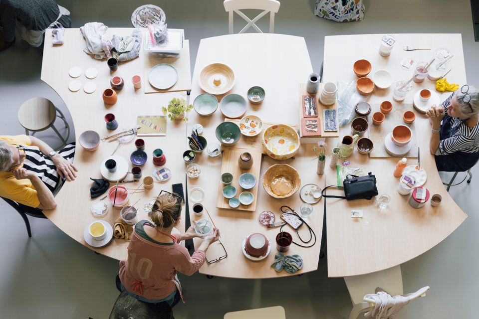 Creatieve workshop mozaïek Kunst op de Hoek, Woerden, Groene Hart, deelnemers werken aan keramiek en servies met glazuur en patronen aan grote tafel met schalen, kopjes en kunstmaterialen in atelier.
