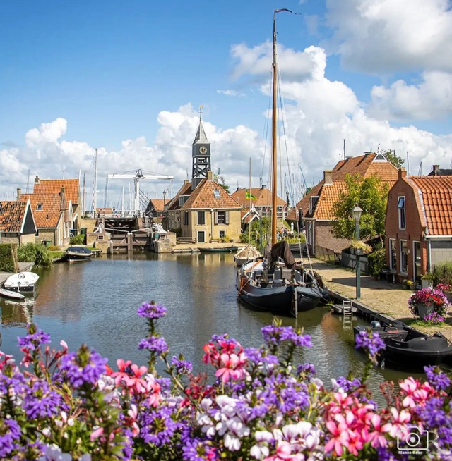 Hindeloopen vanaf een brug gefotografeerd met kleurrijke bloemen op de voorgrond.
