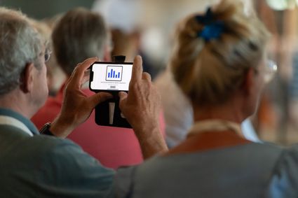 Een man heeft zijn telefoon vast waarop een willekeurige grafiek is te zien.