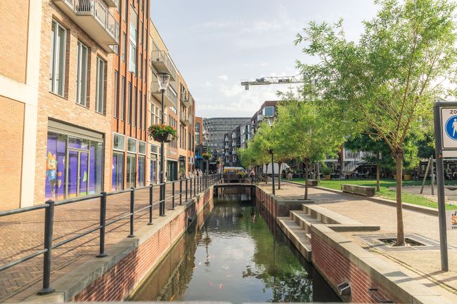 Moderne binnenstad van Veenendaal met winkels, woningen, groen en een watergang door het centrum. De foto laat de combinatie van winkelen, verblijven en openbare ruimte in het stadscentrum zien.