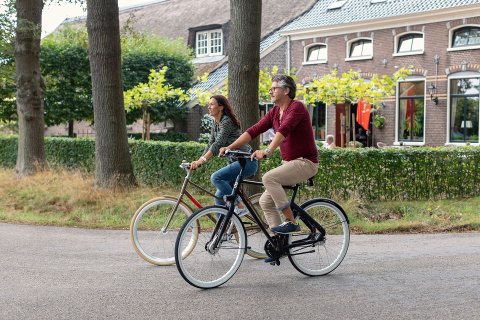 Ein Mann und eine Frau fahren mit dem Fahrrad durch ein Dorf in Drenthe.