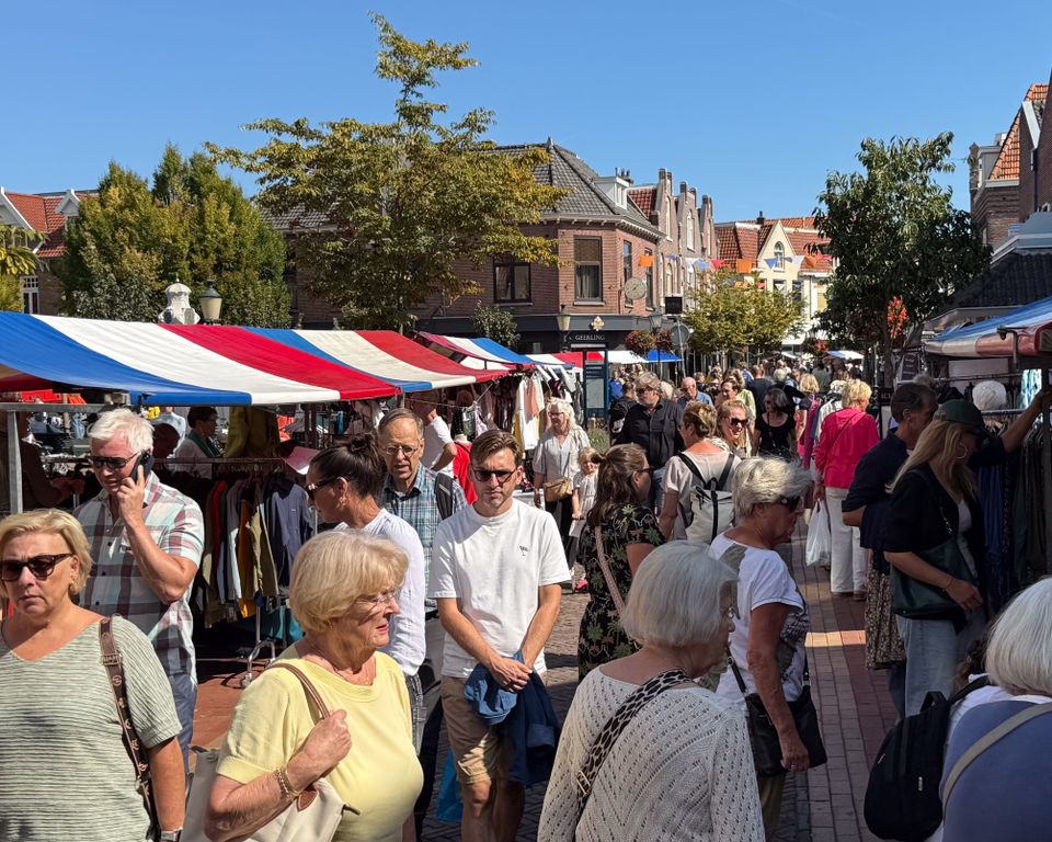 Straat vol kramen en mensen tijdens Koopjesdag in Bussum