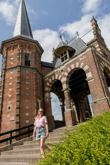 Een vrouw poseert op de trappen van de Waterpoort in Sneek.
