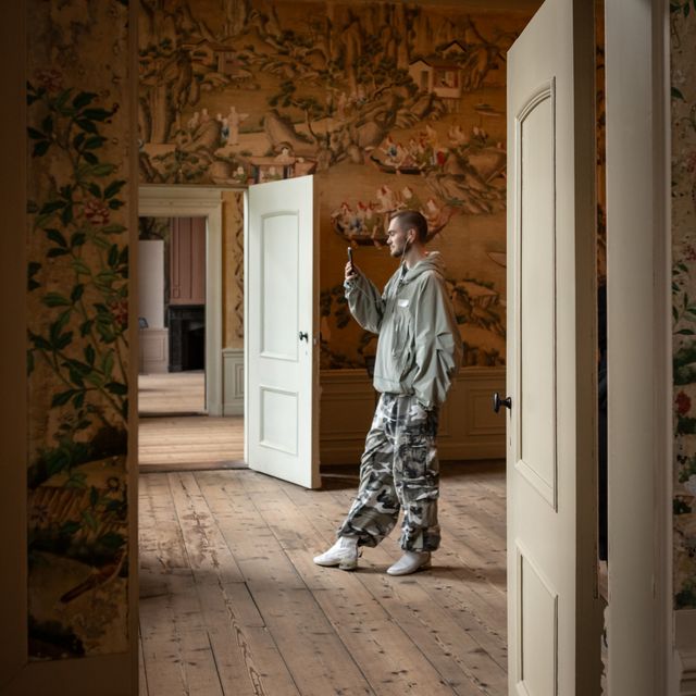 Man bekijkt het interieur en het bijzondere behang van Landhuis Oud Amelisweerd aan de hand van Moving Stories via zijn telefoon