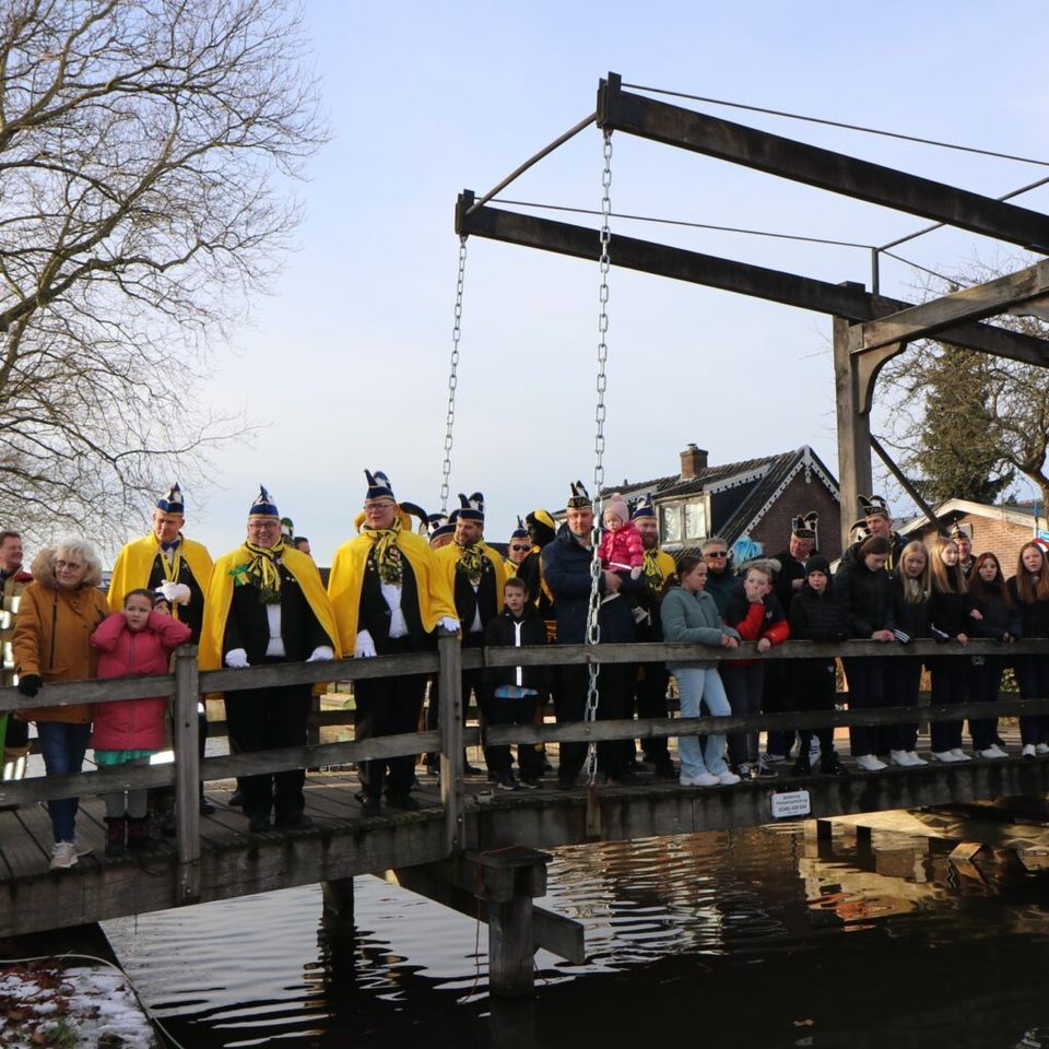 Toeschouwers en carnavalsvierders staan op een houten ophaalbrug in Harmelen tijdens het ophalen van de Grote Kwak, de traditionele start van het carnavalsseizoen