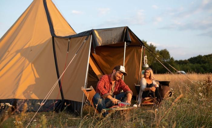 Ein Paar genießt es, draußen zu sein und draußen zu kochen bei ihrem Tipi-Zelt in der Natur von Drenthe.